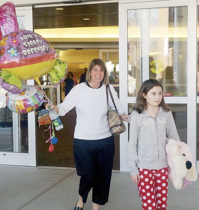 Haley Godin at age 12 with get-well balloons outside the hospital